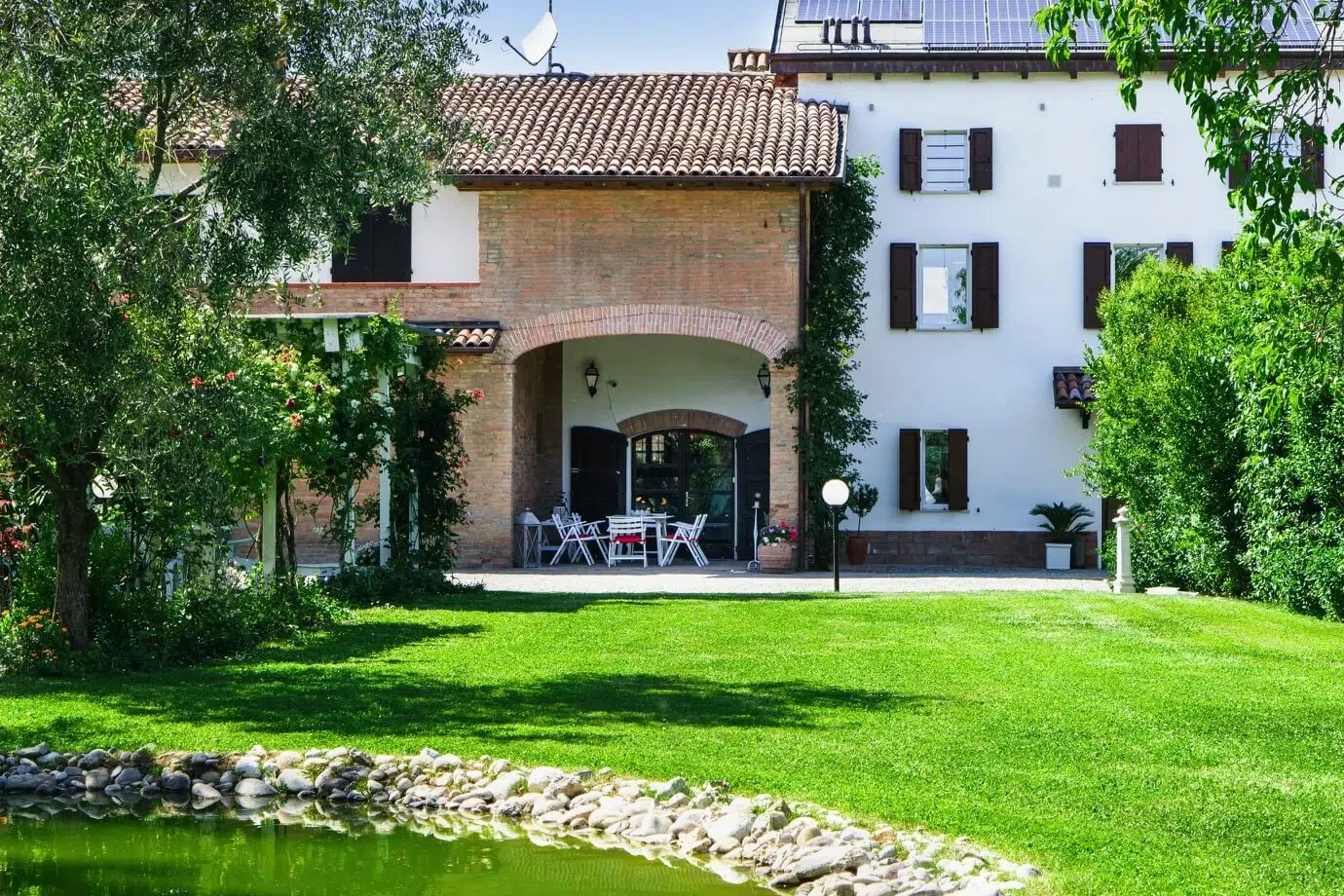 Ca' Ross Resort: facciata con portico in mattoni e prato davanti al laghetto