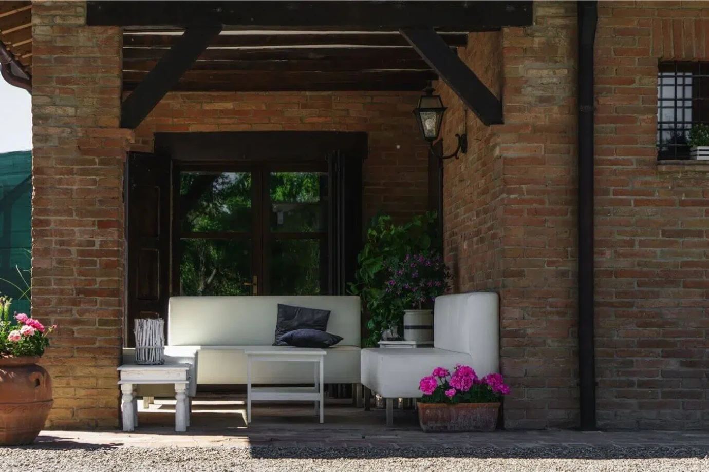 Ca' Ross Resort: portico in mattoni con divanetti bianchi e fiori