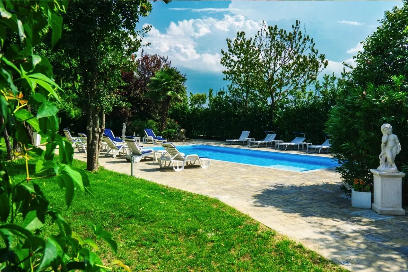 Ca' Ross Resort: piscina con lettini nel giardino, tra gli alberi e una statua