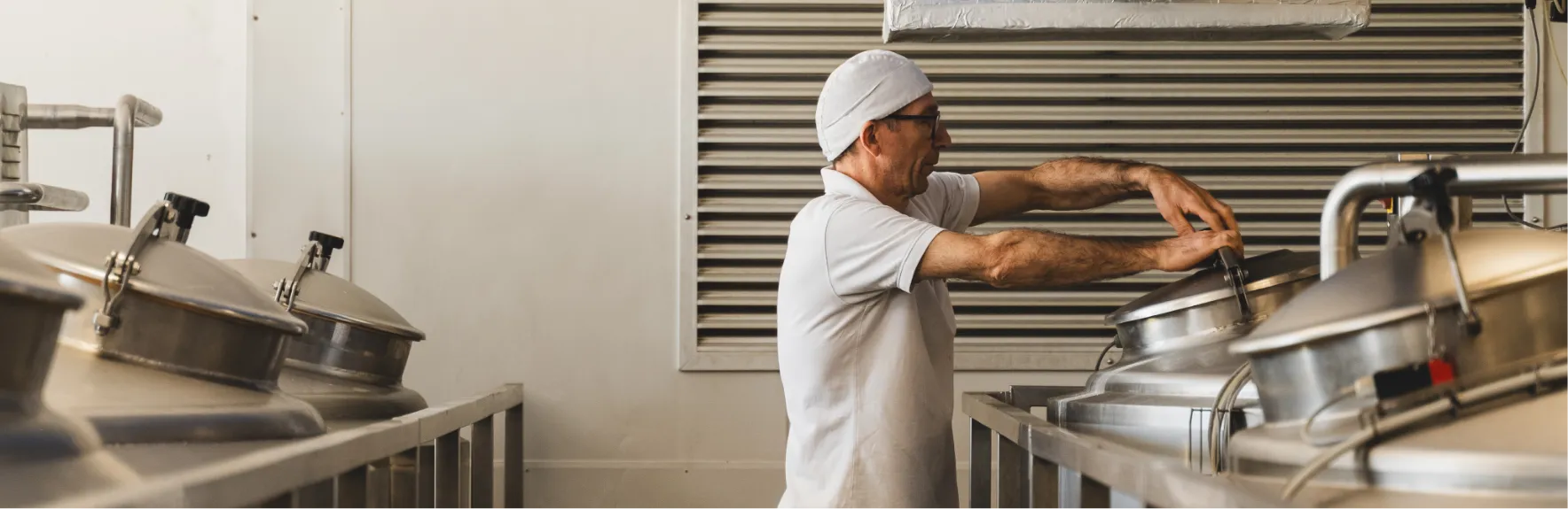 Addetto con cuffia al lavoro tra le caldaie in acciaio dello stabilimento Galli